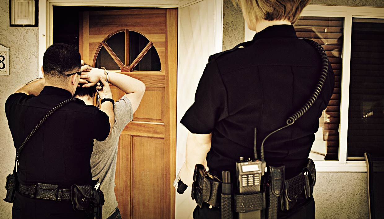 Two police officers arresting a man outside his Philadelphia home on charges related to sex crimes and child pornography